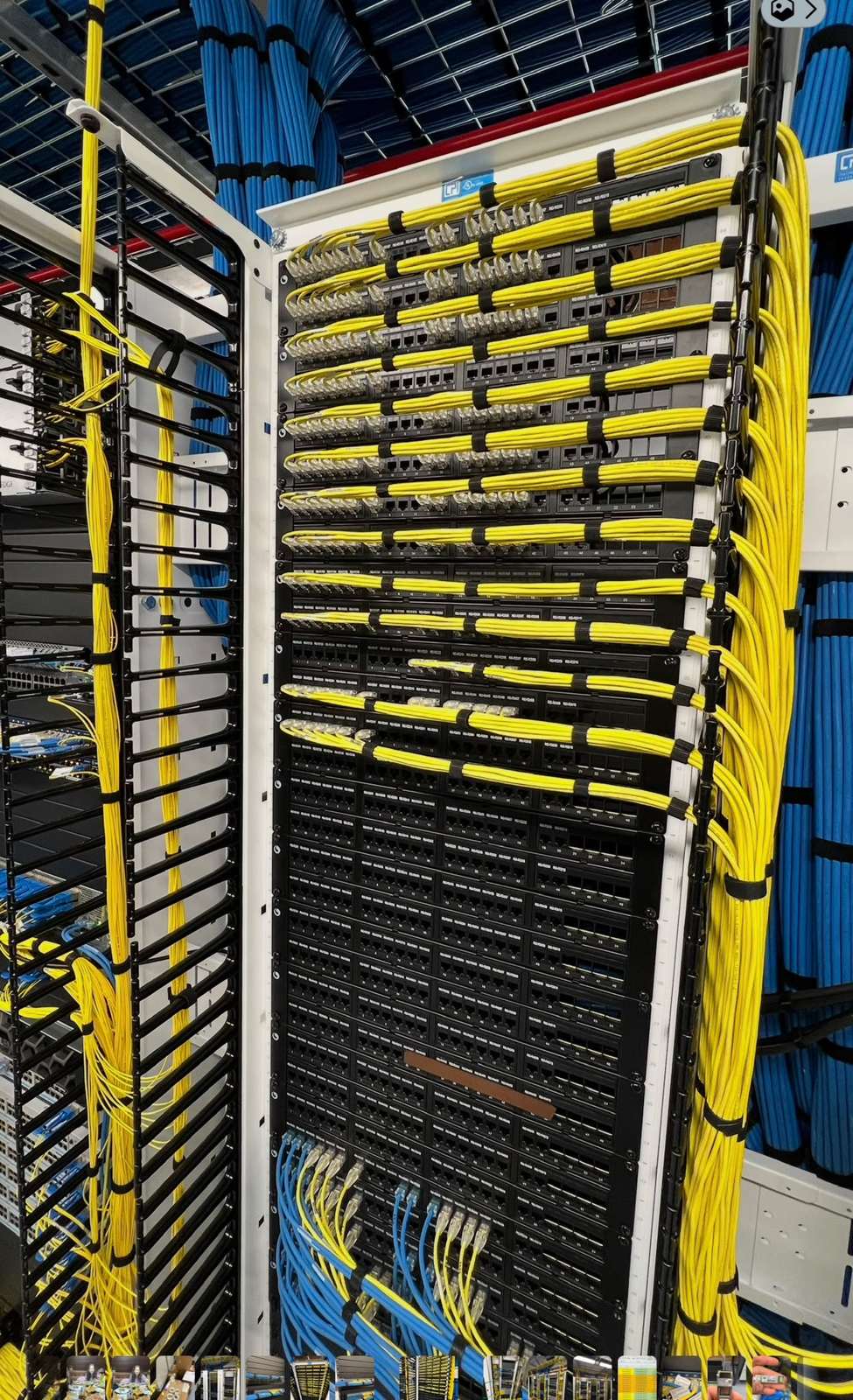 Rack with rows of yellow fibre patch cords dressed neatly into vertical managers