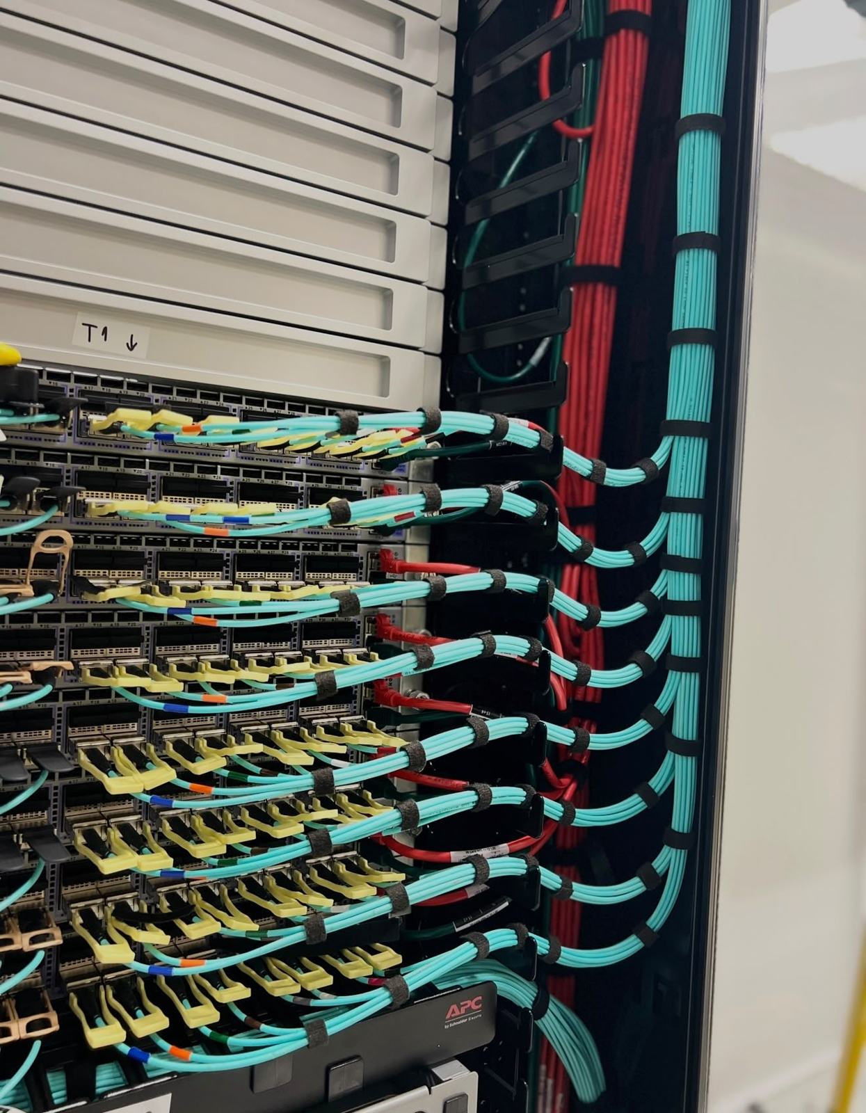 High-density patch panels with aqua fibre cords routed in tidy arcs